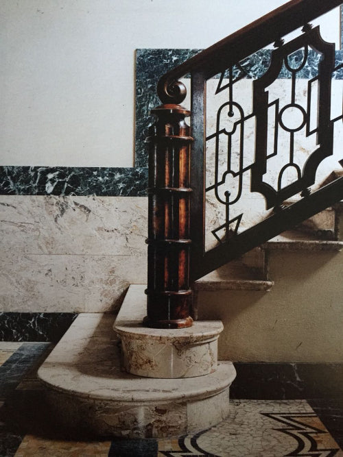 Decorative staircase with marble steps and intricate railing.